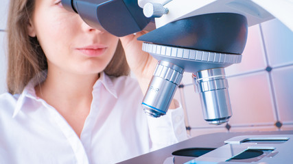 Poster - Young woman technician is examining a histological sample, a biopsy in the laboratory of cancer research