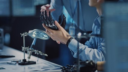 Leinwandbilder - Technological Prosthetic Robot Arm is Tested by Two Professional Development Engineers in a High Tech Research Laboratory with Modern Futuristic Equipment. Man and Female Compare Data on a PC
