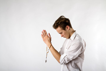 young man is praying with rosary beads.