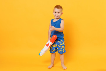 Wall Mural - Kid boy 3-4 years old in blue beach summer clothes hold toy water gun isolated on bright yellow orange wall background children studio portrait. People childhood lifestyle concept. Mock up copy space.