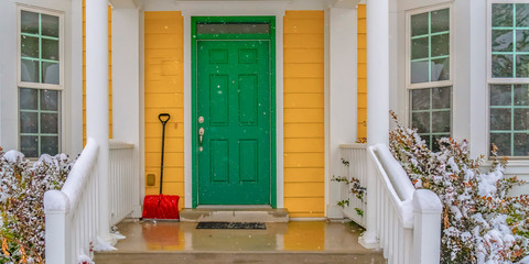 Wall Mural - Snow showel beside the green front door of a home