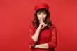 © ViDi Studio - Stunning young woman in lace dress and cap saying hush be quiet with finger on lips shhh gesture isolated on bright red wall background. People sincere emotions, lifestyle concept. Mock up copy space.