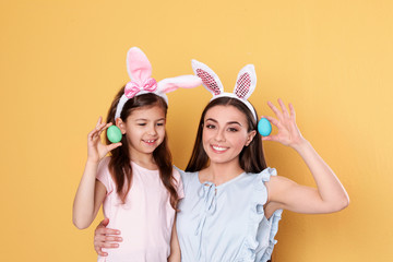 Sticker - Mother and daughter in bunny ears headbands with Easter eggs on color background