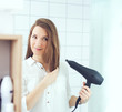 © disq - Beautiful young woman  using hair dryer drying hair in bathroom. Hair care