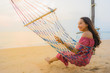 © siraphol - Portrait beautiful young asian woman sitting on the hammock with smile happy neary beach sea and ocean