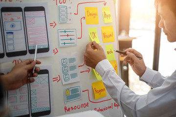 UX designer creative group working about planing mobile application project with sticky notes. User experience concept.