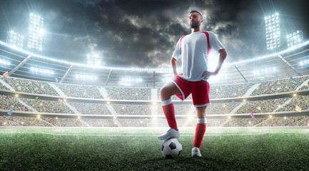 Soccer professional player preparing to the match. Foot on the soccer ball. Night Stadium background. Sport concept