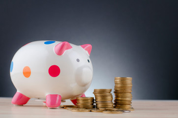 financial and saving money concept, piggy bank with stacking coins on wooden desk over dark background