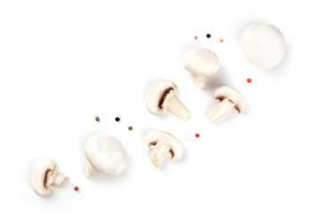 Wall Mural - Champignon mushrooms, whole and sliced, shot from the top on a white background with peppercorns, a flat lay composition with copy space