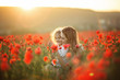 Beautiful child girl with young mother are wearing casual clothes in field of poppy flowers over sunset lights