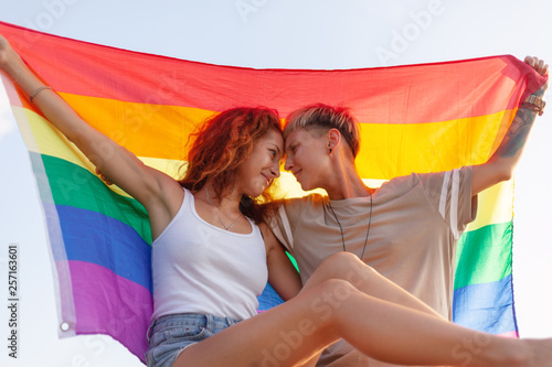 Fotomural Beautiful lesbian young couple gently lovingly hugging with rainbow flag, equal