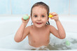 © sementsova321 - Little baby girl holding toy in hands taking bath, plays in water with duck and dolphin. Adorable child being photographed while relaxing with foam in bathroom. Hygiene and health care concept.