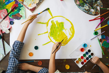 Above view background of two children drawing sun while painting picture together, copy space