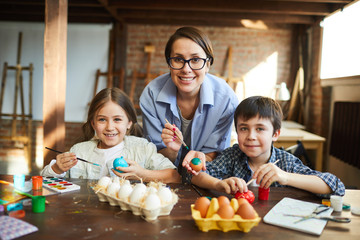 Wall Mural - Portrait of happy family posing while painting Easter eggs together