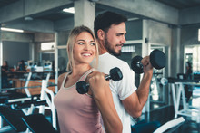 Portrait Of Couple Love In Fitness Training With Dumbbell Equipment., Young Couple Caucasian Are Working Out And Training Together In Gym Club., Sport And Healthy Concept.