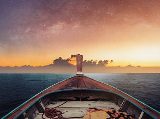 Travelling by boat at night on the ocean, in dawn with starry sky and sunlight over horizon