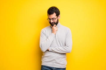 man with beard and turtleneck looking down with the hand on the chin
