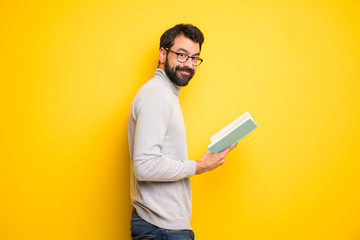 Wall Mural - Man with beard and turtleneck holding a book and enjoying reading