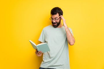 Wall Mural - Man with beard and green shirt surprised while enjoying reading a book