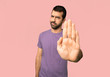 © luismolinero - Handsome man making stop gesture denying a situation that thinks wrong on isolated pink background