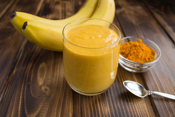 Wall Mural - Smoothies with banana and turmeric on the brown wooden background