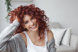 Fototapeta Tulipany - Very attractive young woman close up portrait. Beautiful female indoor. Curly haired lady. Red-haired girl. Redhead with wavy hair.