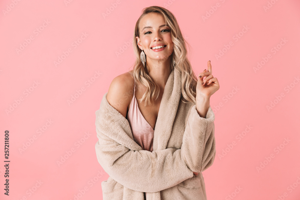 Pretty woman posing isolated over pink wall background dressed in fashion coat. - obrazy, fototapety, plakaty 