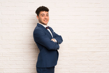 Man in suit and bow tie with arms crossed and looking forward