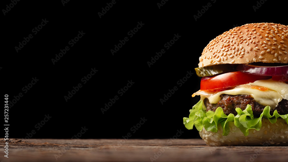 Homemade hamburger close-up with beef, tomato, lettuce, cheese and onion on wooden table. Fastfood on dark background - obrazy, fototapety, plakaty 