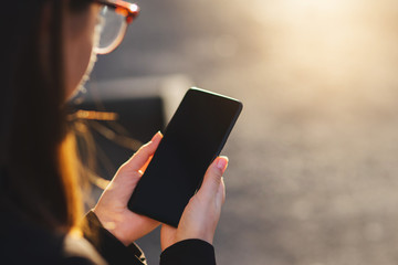 Young woman using modern smartphone device with blank screen during the walk