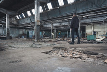 Мужчина в черной одежде стоит на развалинах в старом заброшенном здании