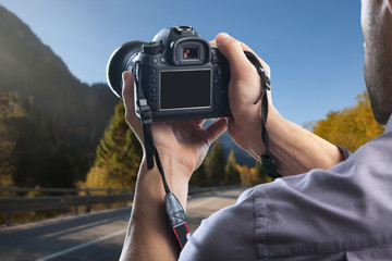 Young man holds modern digital black camera