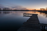 Fototapeta Pomosty - Long jetty on the lake and a colorful sky after sunset