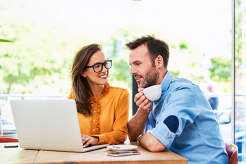 Wall Mural - Couple talking at cafe using laptop and drinking cofee