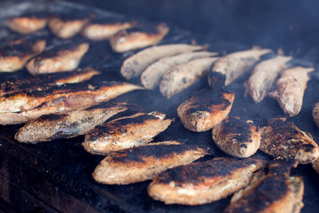 Wall Mural - A lot of fish on the grill. Street food cooking process