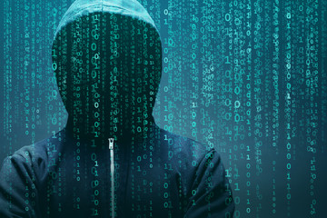 Anonymous computer hacker over abstract digital background. Obscured dark face in mask and hood. Data thief, internet attack, darknet fraud, dangerous viruses and cyber security.