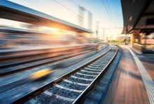 Railway Station With Motion Blur Effect At Sunset. Industrial Landscape With Railroad, Blurred Railway Platform, Sky With Orange Sunlight In The Evening. Railway Junction In Europe. Transportation