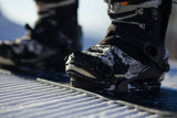 Snowboarder straps in his legs in snowboard boots in modern fast flow bindings with straps.