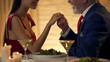 © motortion - Senior gentleman holding hand of tender young wife, romantic date together