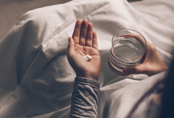 Ill woman in hospital bed take pills