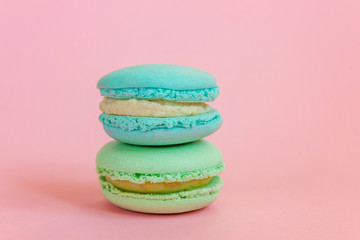 Sweet almond colorful unicorn blue green macaron or macaroon dessert cake isolated on trendy pink pastel background. French sweet cookie. Minimal food bakery concept. Copy space