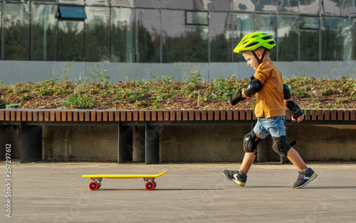 Cuadros en Lienzo A little boy enjoys a yellow cruiser penny plastboard