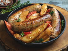 Grilled Chicken Sausages With Fried Potatoes And Peppers In An Iron Pan