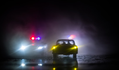 Wall Mural - Police car chasing a car at night with fog background. 911 Emergency response police car speeding to scene of crime. Selective focus