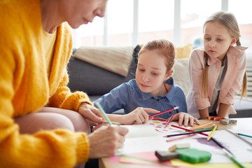 Wall Mural - Portrait of two girls making handmade holiday cards with mother, copy space