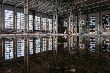 inside of flooded dirty abandoned ruined industrial building with water reflection