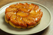Freshly baked homemade Apple Tarte Tatin on a gray plate on a wood table top.	