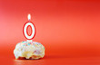 Newborn. Cupcake with white burning candle in the form of number 0. Vivid red background with copy space