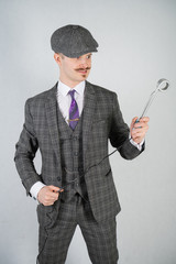 man in a retro suit stands and holds a vintage water boiler on a white studio background alone