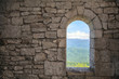 © evgenii - Stone war tower window with motion blurred bird and sea coast view with green tree hills